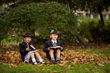 Brother and sister sitting reading among leaves